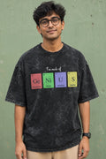 Person wearing a black t-shirt with colorful text design against a green wall.