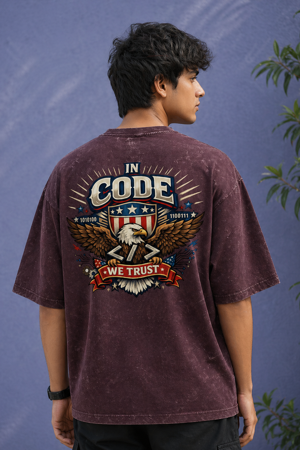 Person wearing a maroon t-shirt with a graphic design on the back against a blue background.