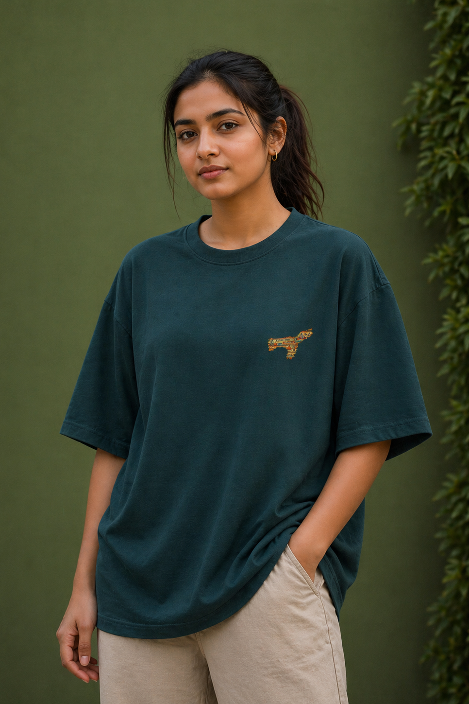 Woman wearing a teal t-shirt with a small logo against a green background